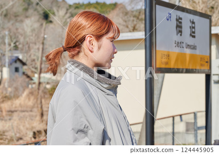 A woman waiting for a train on the station platform in the countryside A woman waiting for a train on the station platform in the countryside 124445905