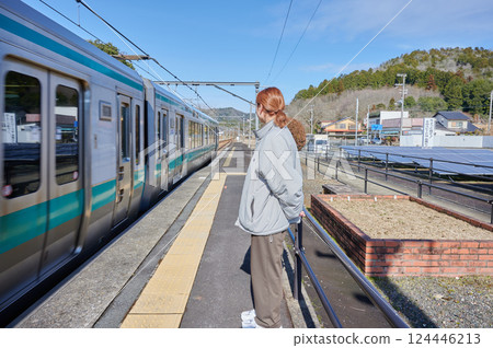 A woman waiting for a train on the station platform in the countryside 124446213