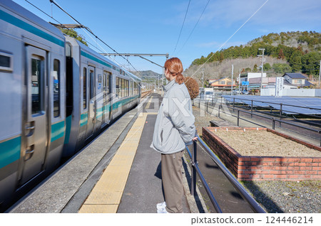 A woman waiting for a train on the station platform in the countryside 124446214