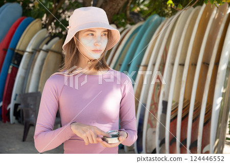 Portrait of young woman applies protective zinc on face before surfing. Best protection from active sun and UV for long time. Eco-friendly product that is safe for corals in ocean. Portrait of young woman applies protective zinc on face before surfing. Best protection from active sun and UV for long time. Eco-friendly product that is safe for corals in ocean. 124446552