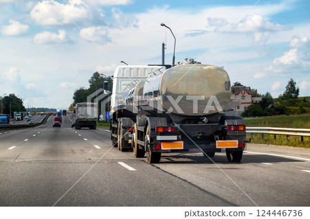 A tanker truck with a tank semi-trailer transports milk and food liquids. Truck on the highway in summer, industry. Copy space for text, traffic 124446736