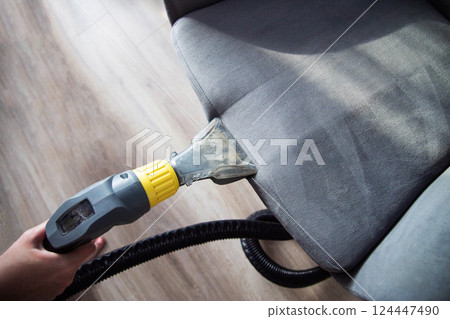 Services for washing and cleaning upholstered furniture with a vacuum cleaner. Cleaning dirty gray chairs in the apartment, industry 124447490
