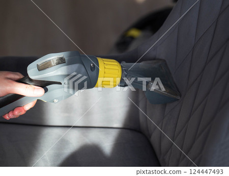 Cleaning the upholstery of a gray chair from dirt with a washing vacuum cleaner. Cleaning services, close-up. Industry 124447493