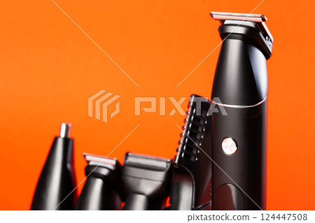 Modern set of hair trimmer with different attachments on a red background, close-up. Copy space for text 124447508