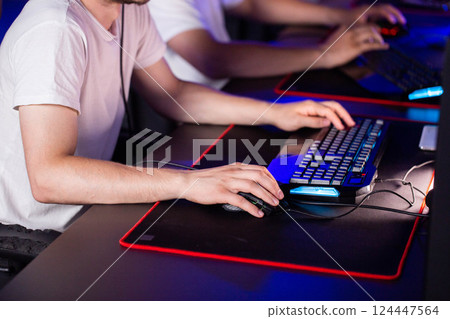 Gamer plays video game on PC at computer club with his team, professional cyber sport tournament, gaming mouse RGB lighting keyboard on mat close up. E-sport championship. Multiplayer shooter strategy 124447564