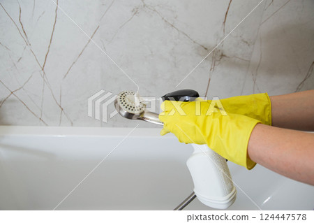 Washing the shower head in the bathroom with a cleaning and bleaching product. Cleaning service, copy space for text Washing the shower head in the bathroom with a cleaning and bleaching product. Cleaning service, copy space for text 124447578