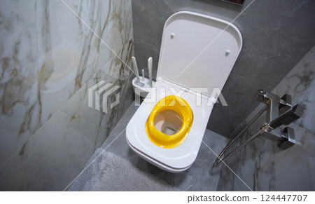 Yellow child toilet seat for children in the toilet. Convenience and comfort for the child on the toilet, close-up Yellow child toilet seat for children in the toilet. Convenience and comfort for the child on the toilet, close-up 124447707