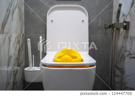 Yellow child toilet seat for children in the toilet. Convenience and comfort for the child on the toilet, close-up Yellow child toilet seat for children in the toilet. Convenience and comfort for the child on the toilet, close-up 124447708