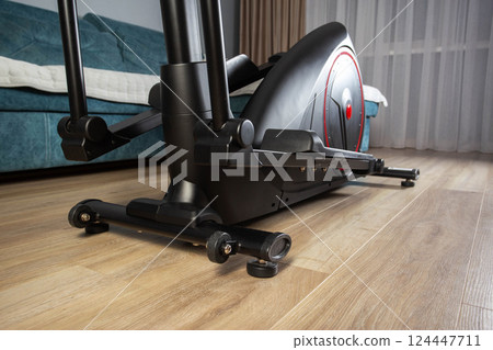 Modern Elliptical Trainer in the Room at Home. Concept of Exercising at Home, fitness Modern Elliptical Trainer in the Room at Home. Concept of Exercising at Home, fitness 124447711