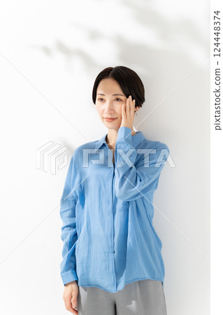 Woman touching her cheek, sunlight filtering through the trees, beauty 124448374