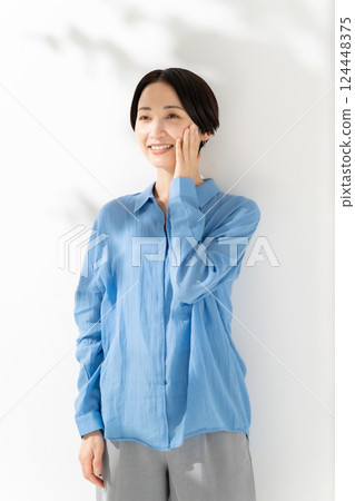 Woman touching her cheek, sunlight filtering through the trees, beauty 124448375