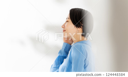 Woman touching her cheek, sunlight filtering through the trees, beauty, landscape 124448384