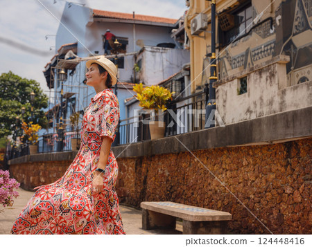 woman in dress and hat exploring vibrant streets of Malacca, Malaysia. 124448416