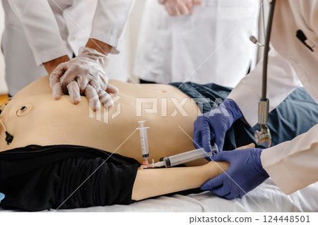 Doctors practicing cardiopulmonary resuscitation and intravenous injection on medical manikin Doctors practicing cardiopulmonary resuscitation and intravenous injection on medical manikin 124448501
