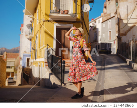 Woman strolls through colorful streets of Spanish coastal town 124448666