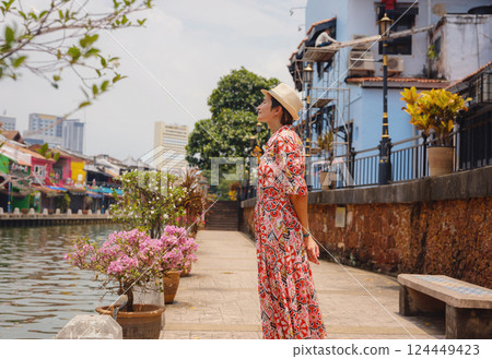 woman in dress and hat exploring vibrant streets of Malacca, Malaysia. 124449423