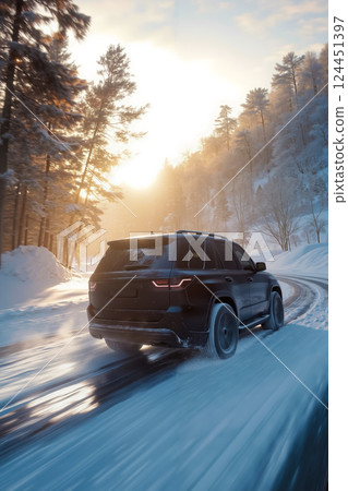 A black car driving down a snowy road in the woods 124451397