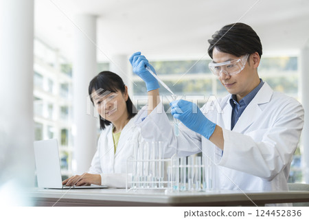 Middle-aged man and woman wearing white coats conducting experiments Middle-aged man and woman wearing white coats conducting experiments 124452836