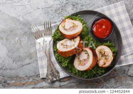 Juicy turkey roll with bacon, onions and mushrooms close-up in a plate. Horizontal top view 124452844