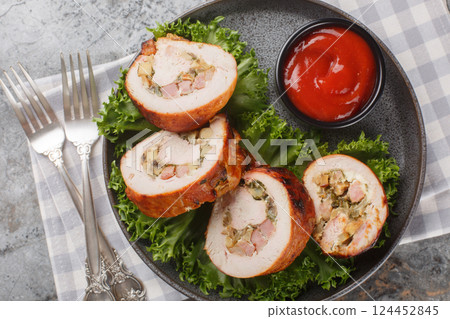 Festive sliced turkey fillet roll with bacon, onions and mushrooms served with ketchup close-up in a plate. Horizontal top view Festive sliced turkey fillet roll with bacon, onions and mushrooms served with ketchup close-up in a plate. Horizontal top view 124452845