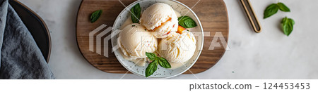 Peach ice cream scoops topped with crumbled biscuits and basil leaves, served in a bowl 124453453