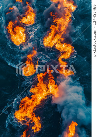 Aerial view of orange flames burning on blue water surface creating abstract shapes Aerial view of orange flames burning on blue water surface creating abstract shapes 124453469