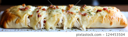 Close-up of a freshly baked chicken bacon ranch stromboli, featuring golden-brown crust, melted cheese, and savory filling 124453504
