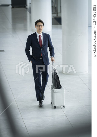 一位 40 多歲的商人提著行李箱行走 124453882