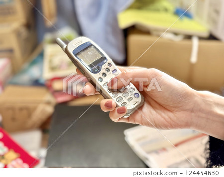 Woman's hand holding an old PHS during decluttering 124454630