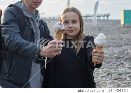 Portrait of child daughter and her father holding ice cream outdoors. Happy family, childhood  124454864