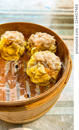Chinese steamed dumpling dim sum in bamboo basket on wooden table 124457468