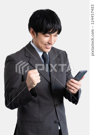 A male businessman who is happy to see the screen of his smartphone A male businessman who is happy to see the screen of his smartphone 124457483