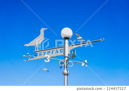 BURGAS, BULGARIA - MARCH 21, 2025: Seagull shaped weather vane with Cyrillic city name, clear vivid sky, flying birds seagulls. Seaside vibe, travel direction, symbolic motion in open coastal space BURGAS, BULGARIA - MARCH 21, 2025: Seagull shaped weather vane with Cyrillic city name, clear vivid sky, flying birds seagulls. Seaside vibe, travel direction, symbolic motion in open coastal space 124457527