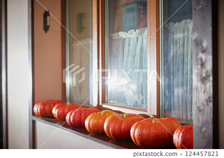 Halloween concept. A lot of pumpkins are lying on the window of the house. Decor for Halloween celebration 124457821