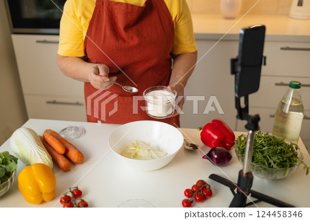 Senior Woman Adding Sugar to a Bowl for Cooking in the Kitchen Senior Woman Adding Sugar to a Bowl for Cooking in the Kitchen 124458346