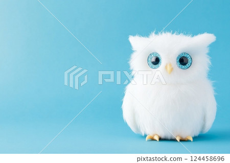 Fluffy owl with gemstone eyes on blue canvas background in soft daylight 124458696