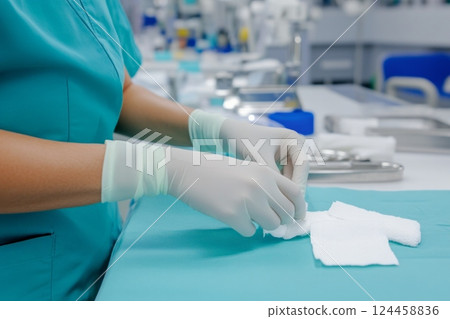Nurse carefully dressing a forearm wound with sterile gauze and gloves in a medical facility 124458836