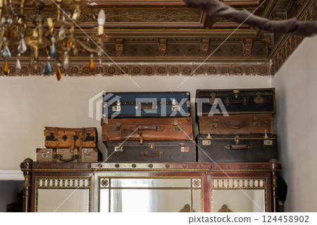 Stacked vintage suitcases on top of a decorated wooden wardrobe in a classic interior Stacked vintage suitcases on top of a decorated wooden wardrobe in a classic interior 124458902
