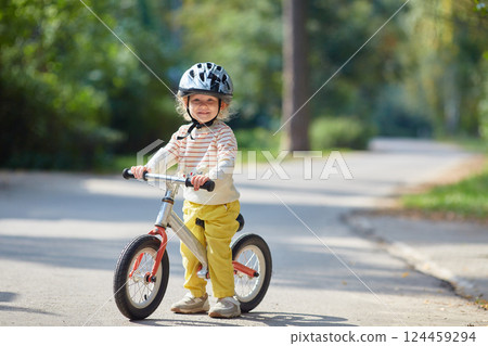 satisfied child on a balance bike in a helmet. On a sunny summer day. 124459294