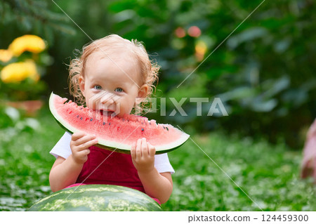 kid eats a big piece of watermelon on the street on a summer day kid eats a big piece of watermelon on the street on a summer day 124459300