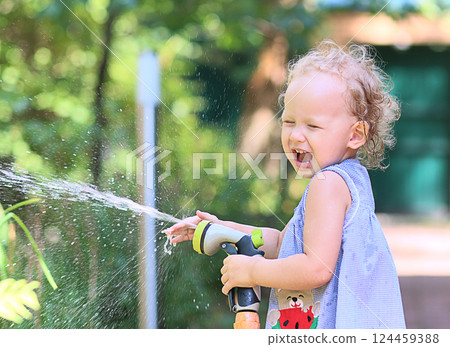 little girl cheerfully splashes water from a watering hose on a sunny summer day little girl cheerfully splashes water from a watering hose on a sunny summer day 124459388