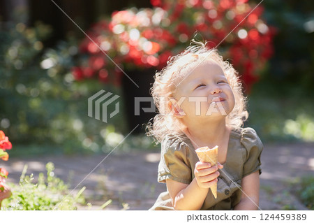 Happy curly-haired kid with ice cream on a sunny summer day. 124459389