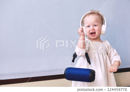 Girl listens to music sings and dances in headphones with a music speaker in her hands. Copy space 124459778