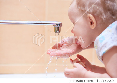 The child drinks running water from the tap. 124459902