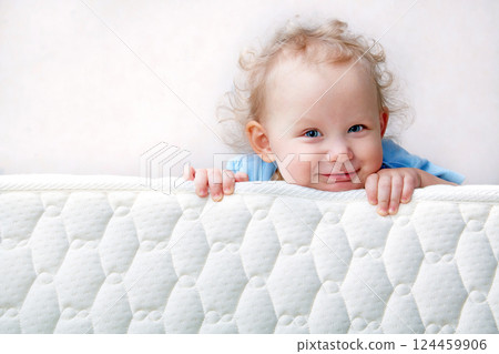 Baby on the bed mattress close-up. The sidewall of the mastras is stitched with finishing lines. Baby on the bed mattress close-up. The sidewall of the mastras is stitched with finishing lines. 124459906