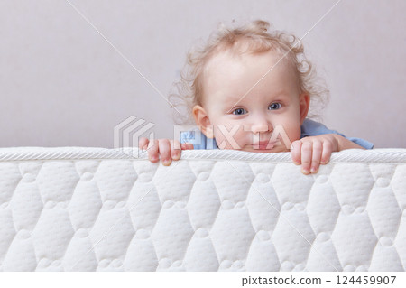 Cute thoughtful curly-haired todd is lying on the mattress. Copy space. Cute thoughtful curly-haired todd is lying on the mattress. Copy space. 124459907