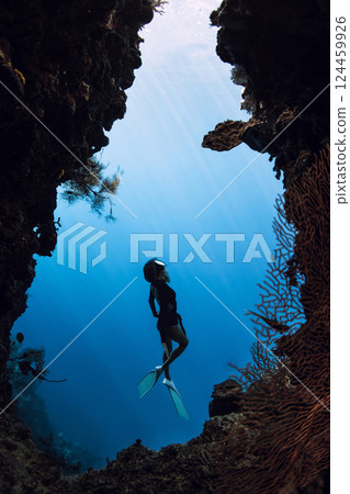 Woman dives in underwater cave on Menjangan island, Bali. Freediver swims in cave Woman dives in underwater cave on Menjangan island, Bali. Freediver swims in cave 124459926