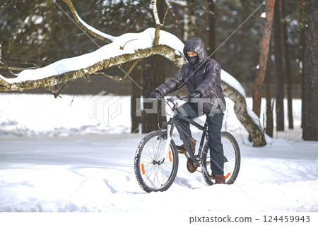 Winter sports. Cycling trips. A young man in black clothes rides a bicycle 124459943