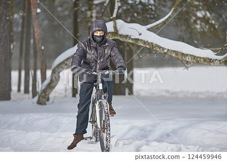 Active winter recreation. A teenager in a buff and black clothes rides a bike in winter Active winter recreation. A teenager in a buff and black clothes rides a bike in winter 124459946