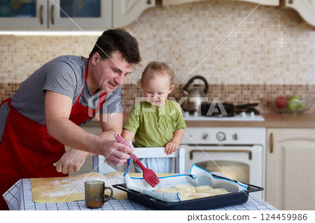 Father and child bake pies, cook food and have fun in the kitchen. Homemade food and a little helper. Happy parenthood Father and child bake pies, cook food and have fun in the kitchen. Homemade food and a little helper. Happy parenthood 124459986